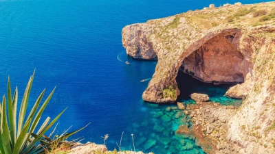 Tourist boat passing through the natural rock arch at the Blue Grotto, Malta