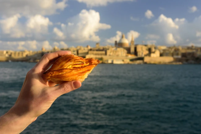 Pastizzi, Maltese ricotta pastries, with Valletta in the background